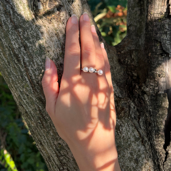 Vue de la bague Trinity portée par mannequin avec focus sur  la disposition des 3 perles blanches 