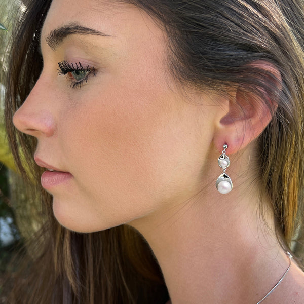Vue portée sur mannequin  des Boucles pétales constituées de deux perles blanches de 8 et 4.5 mm de diamètre logées dans une corolle en argent 925